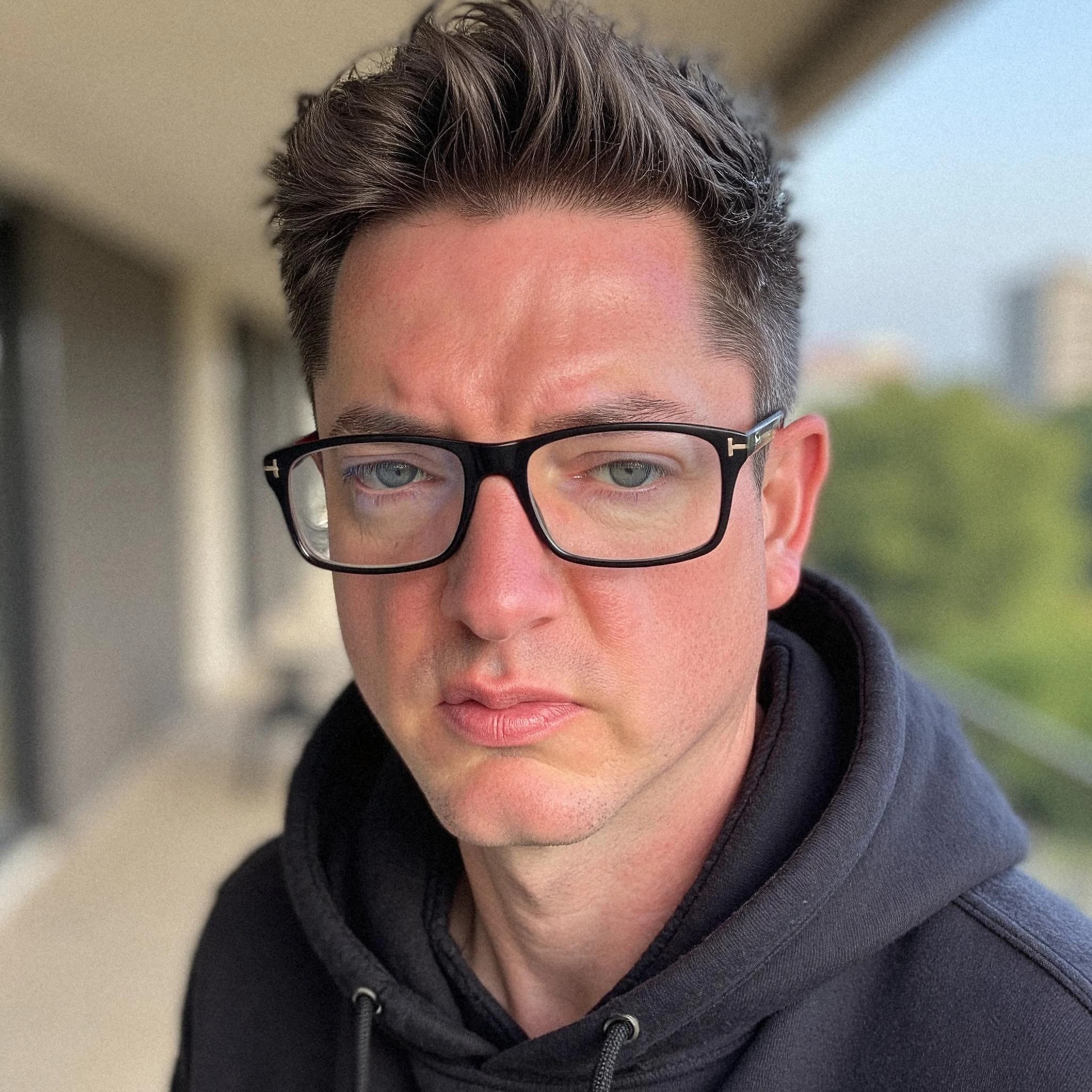 Professional headshot example: Man Balcony Black Hoodie Glasses — LinkedInHeadshots.ai