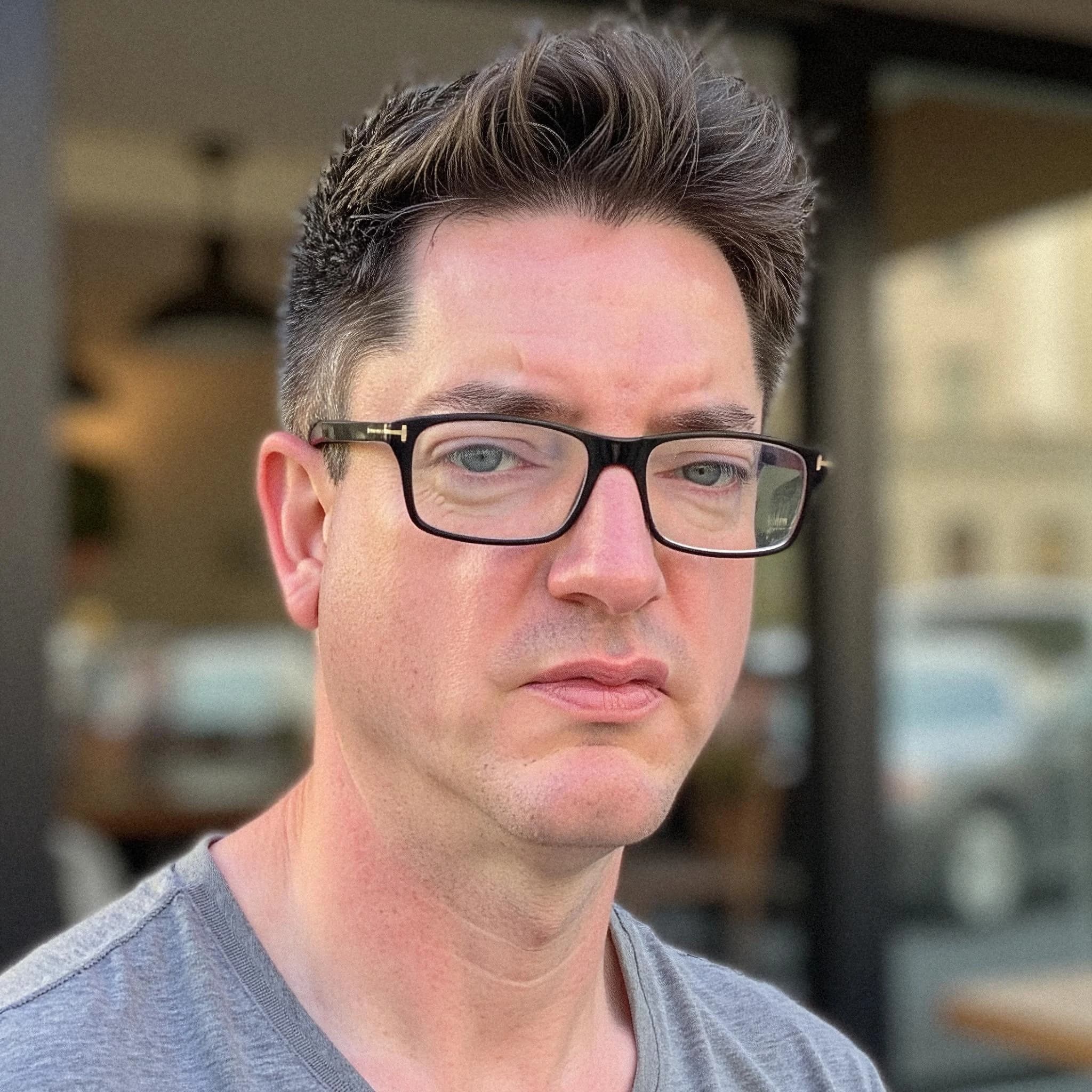 Professional headshot example: Man Cafe Gray Shirt Glasses — LinkedInHeadshots.ai