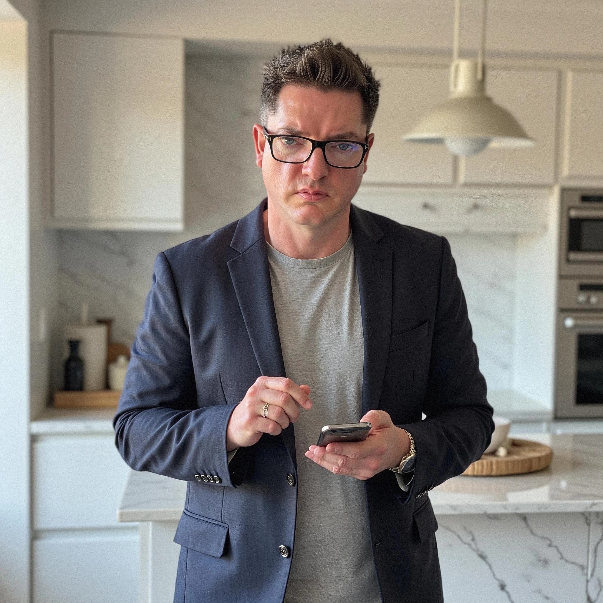 Professional headshot example: Man Kitchen Suit Holding Phone — LinkedInHeadshots.ai