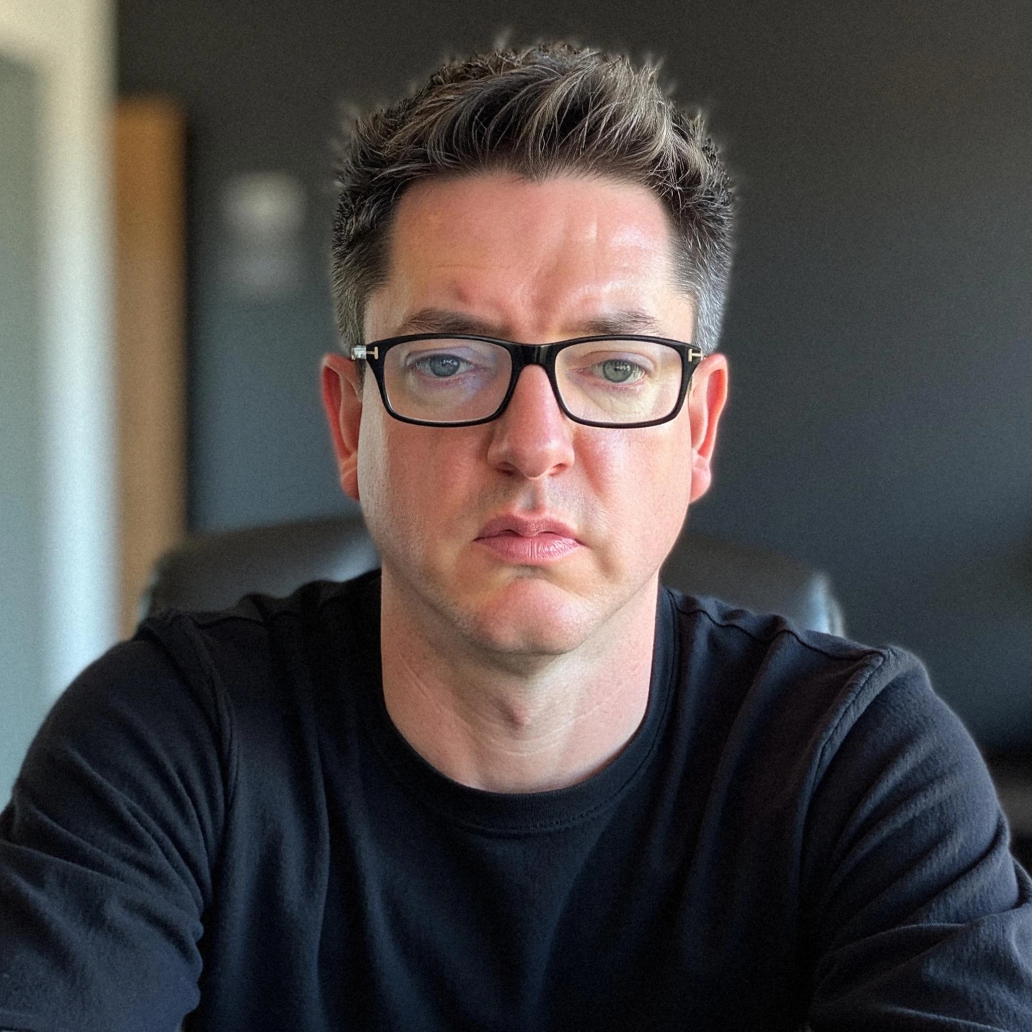 Professional headshot example: Man Office Black Shirt Sitting 3 — LinkedInHeadshots.ai