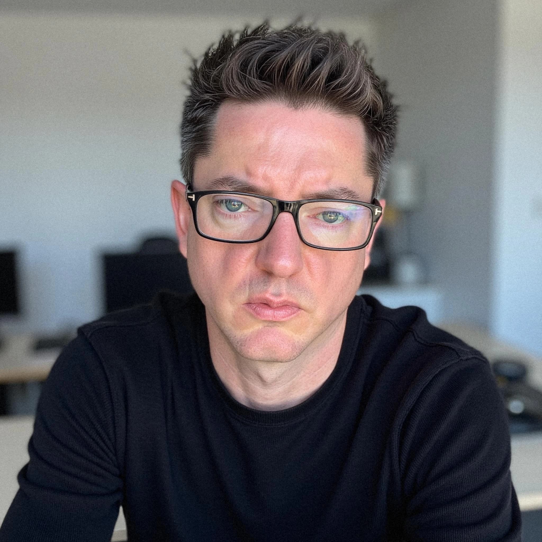 Professional headshot example: Man Office Black Shirt Sitting 4 — LinkedInHeadshots.ai