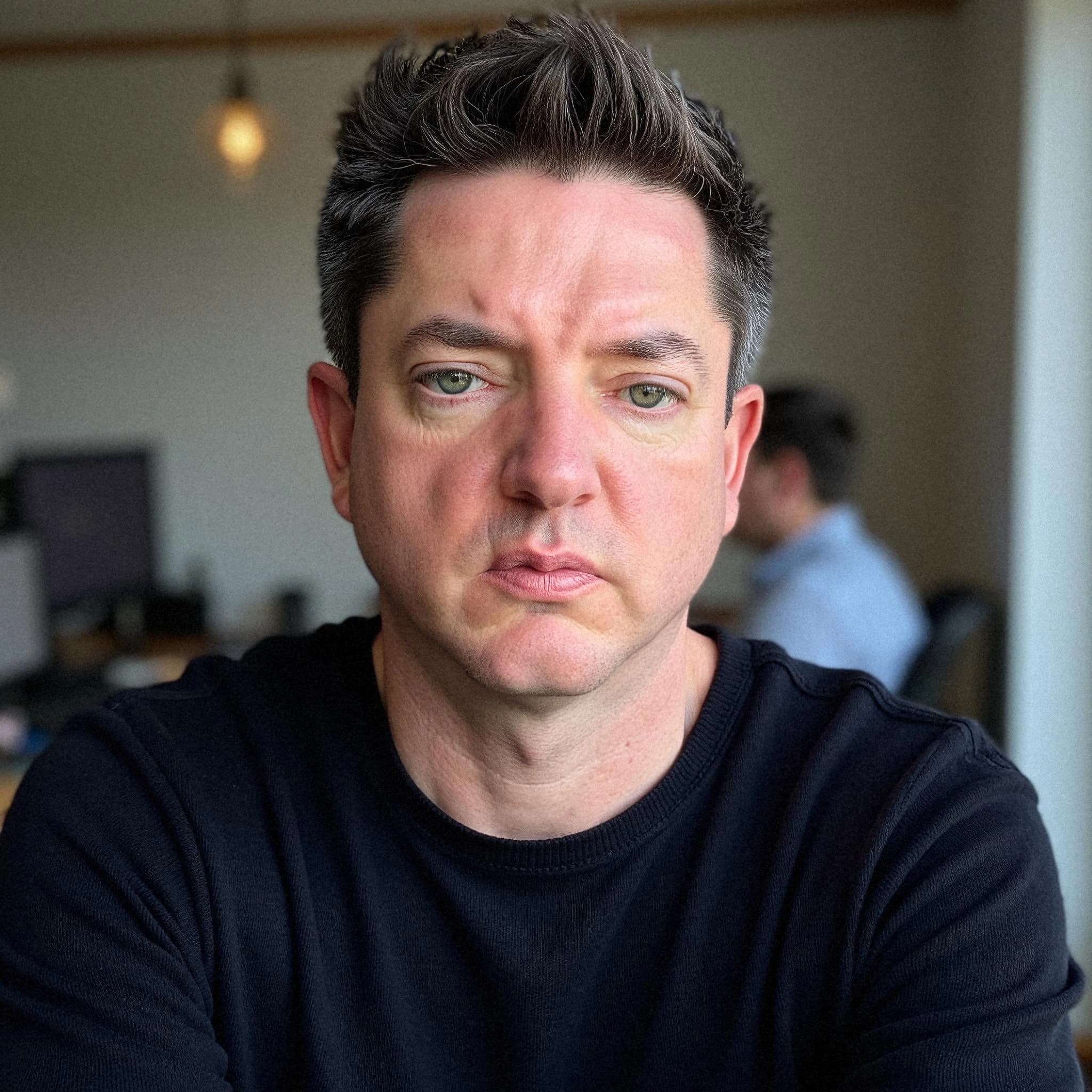 Professional headshot example: Man Office Black Sweater Sitting — LinkedInHeadshots.ai