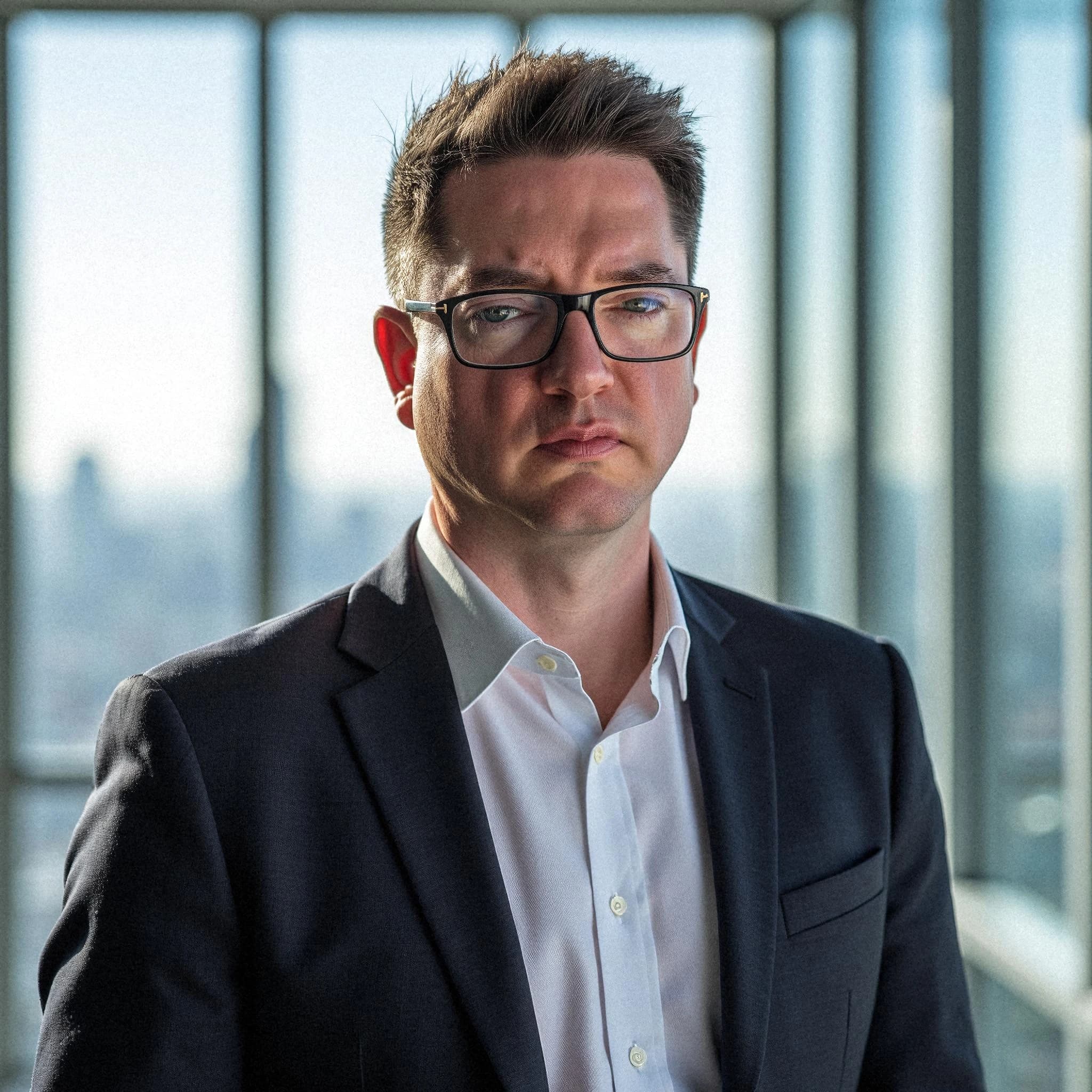 Professional headshot example: Man Office Suit Glasses Serious 7 — LinkedInHeadshots.ai