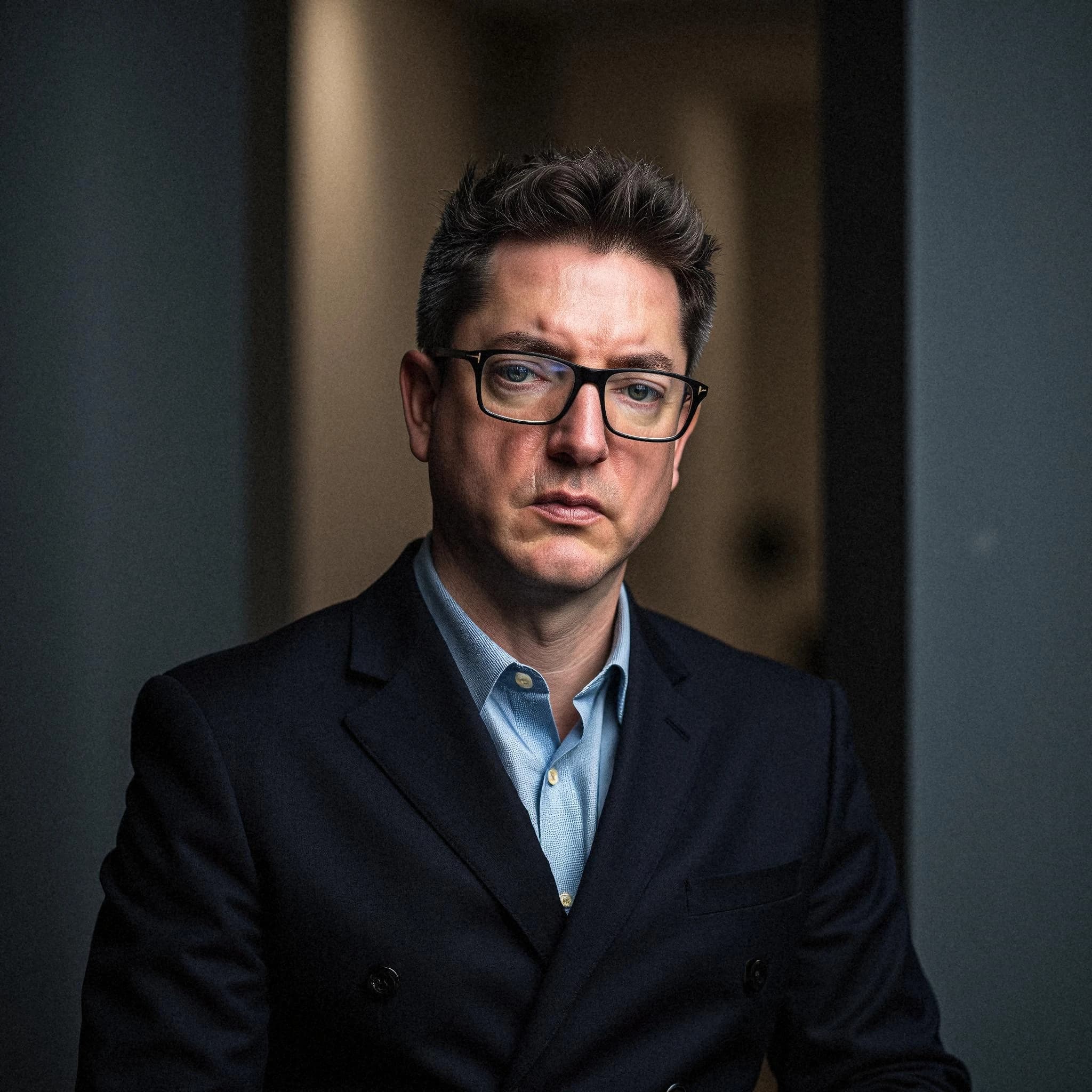 Professional headshot example: Man Office Suit Glasses Serious 9 — LinkedInHeadshots.ai