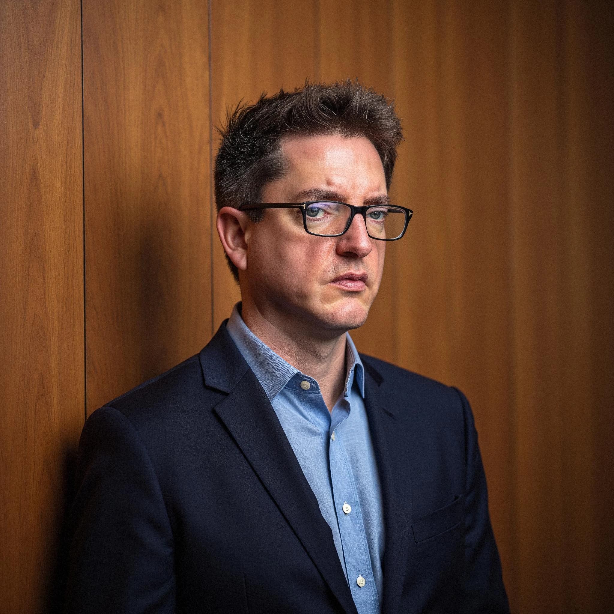 Professional headshot example: Man Office Suit Glasses Standing 2 — LinkedInHeadshots.ai