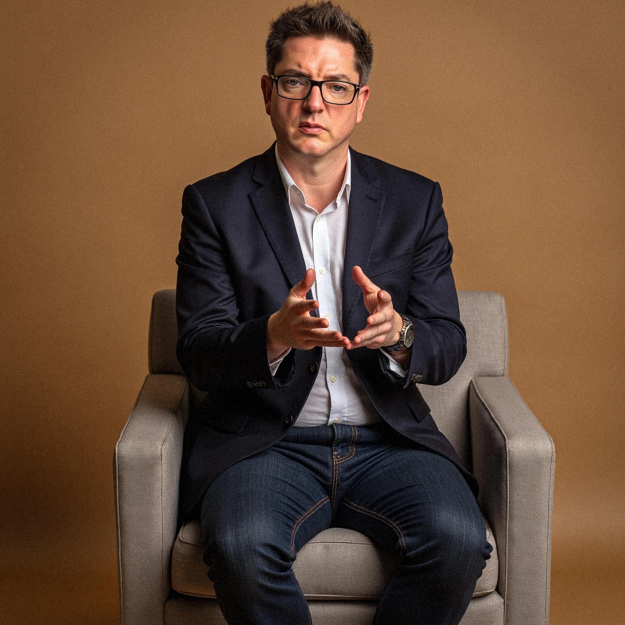 Professional headshot example: Man Office Suit Sitting Chair 3 — LinkedInHeadshots.ai