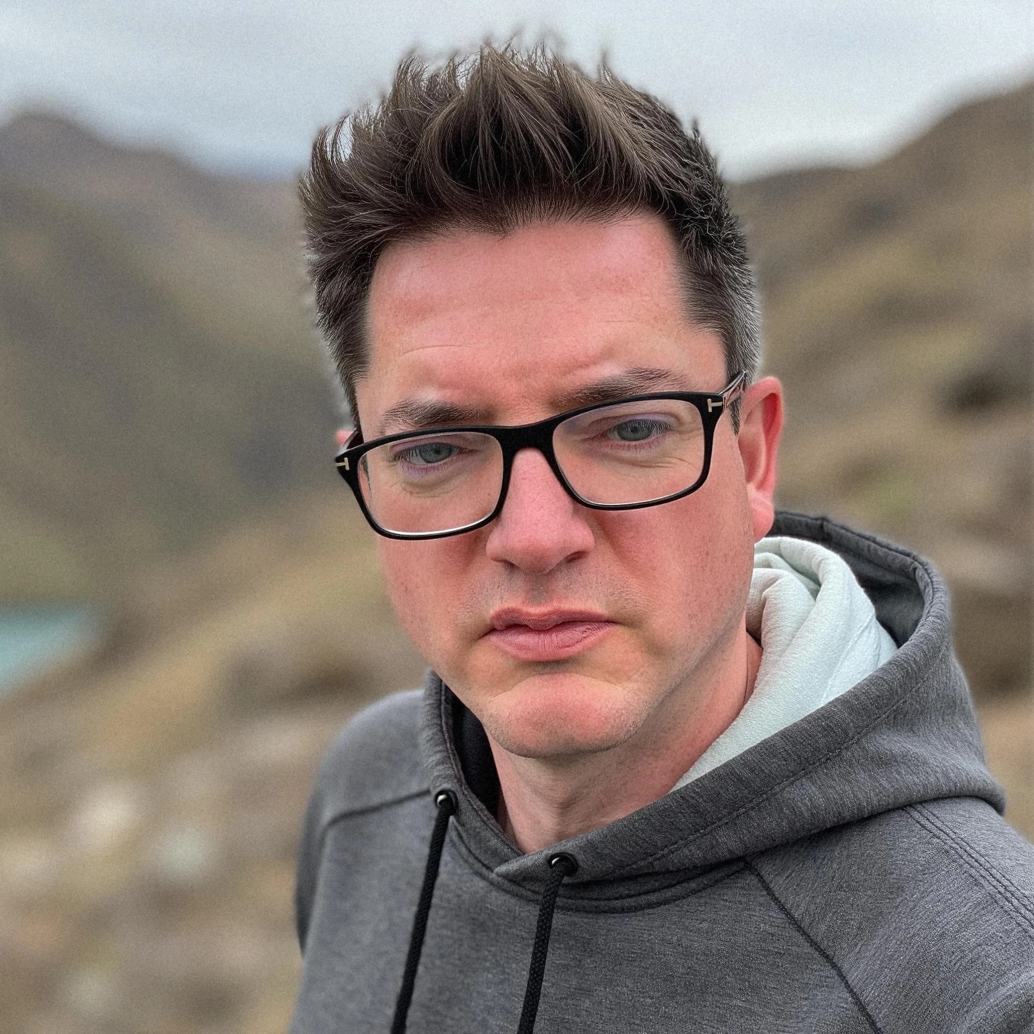Professional headshot example: Man Outdoors Glasses Grey Hoodie — LinkedInHeadshots.ai