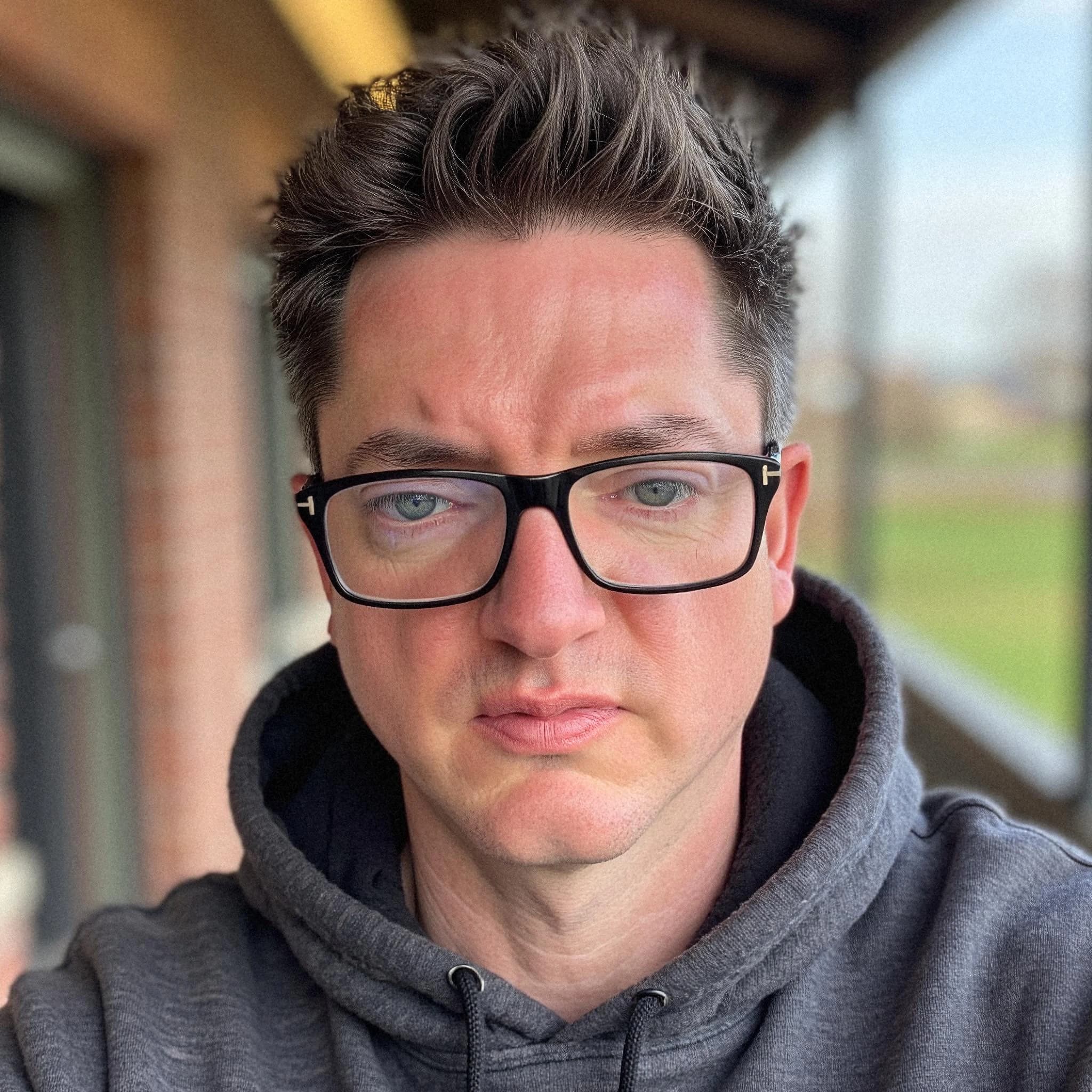 Professional headshot example: Man Outdoors Gray Hoodie Glasses — LinkedInHeadshots.ai