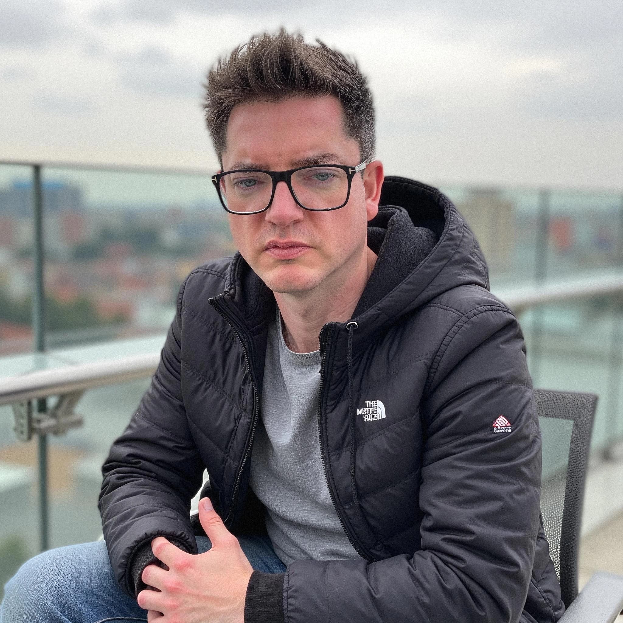 Professional headshot example: Man Rooftop Black Jacket Sitting — LinkedInHeadshots.ai