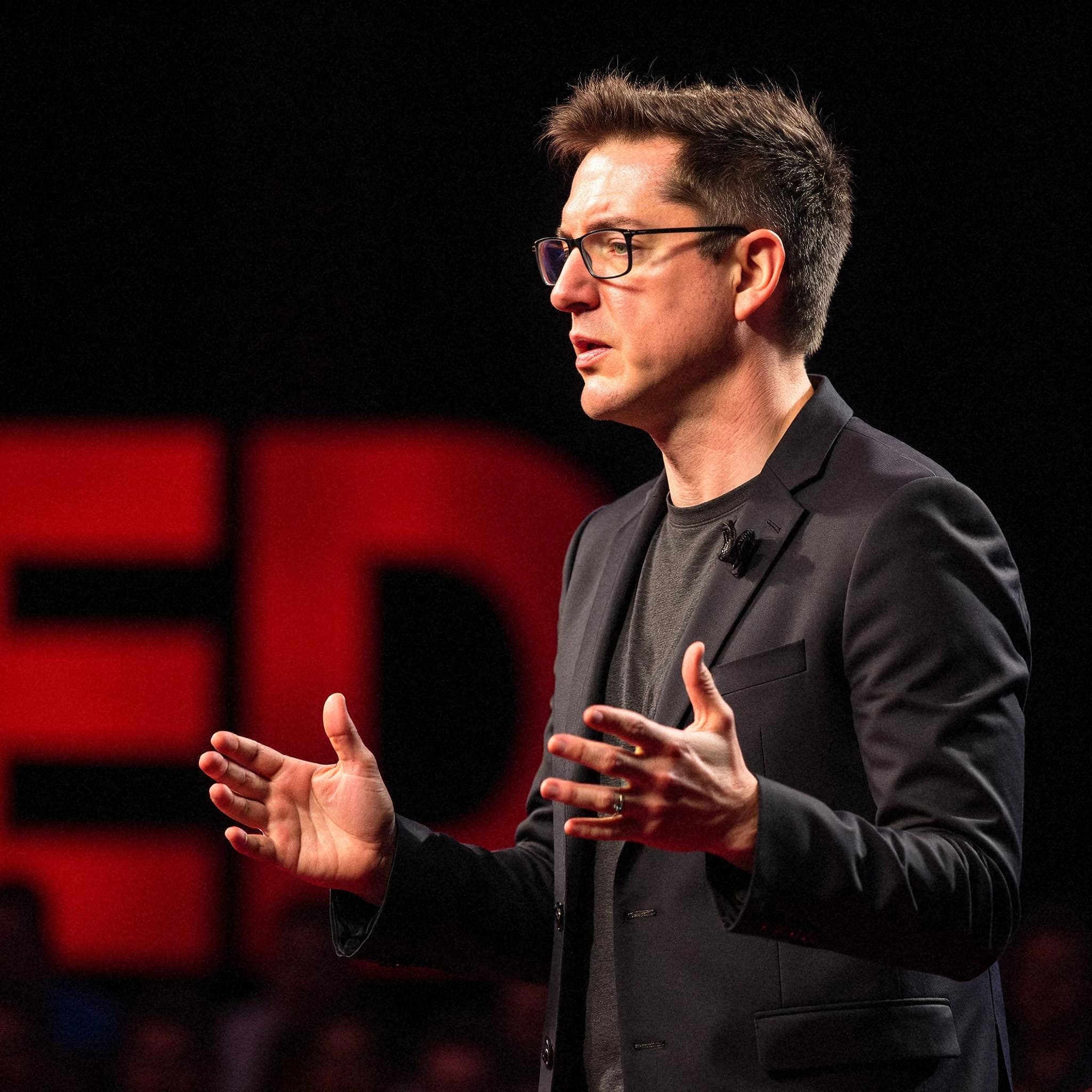 Professional headshot example: Man Stage Black Suit Speaking — LinkedInHeadshots.ai