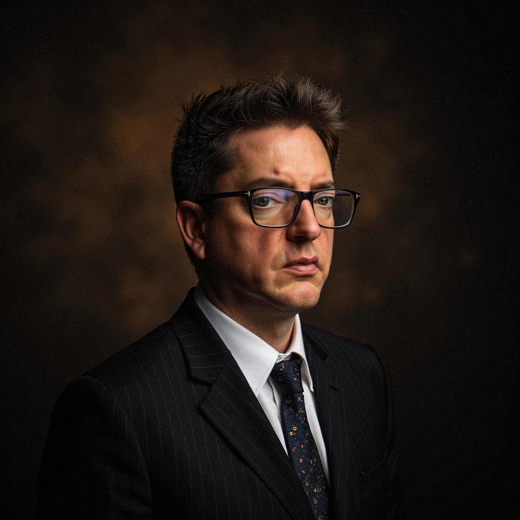 Professional headshot example: Man Studio Suit Glasses Serious 11 — LinkedInHeadshots.ai