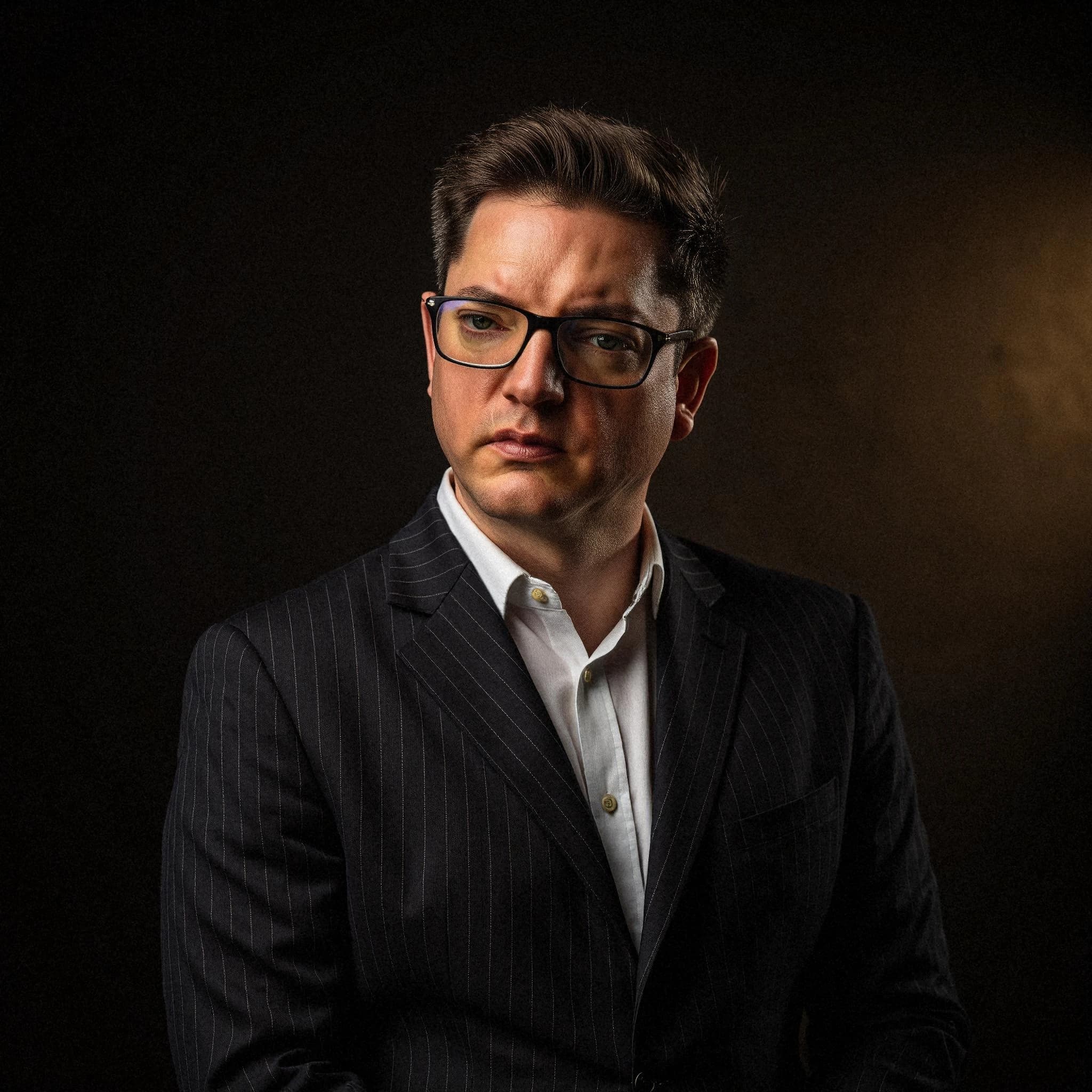 Professional headshot example: Man Studio Suit Glasses Serious 4 — LinkedInHeadshots.ai