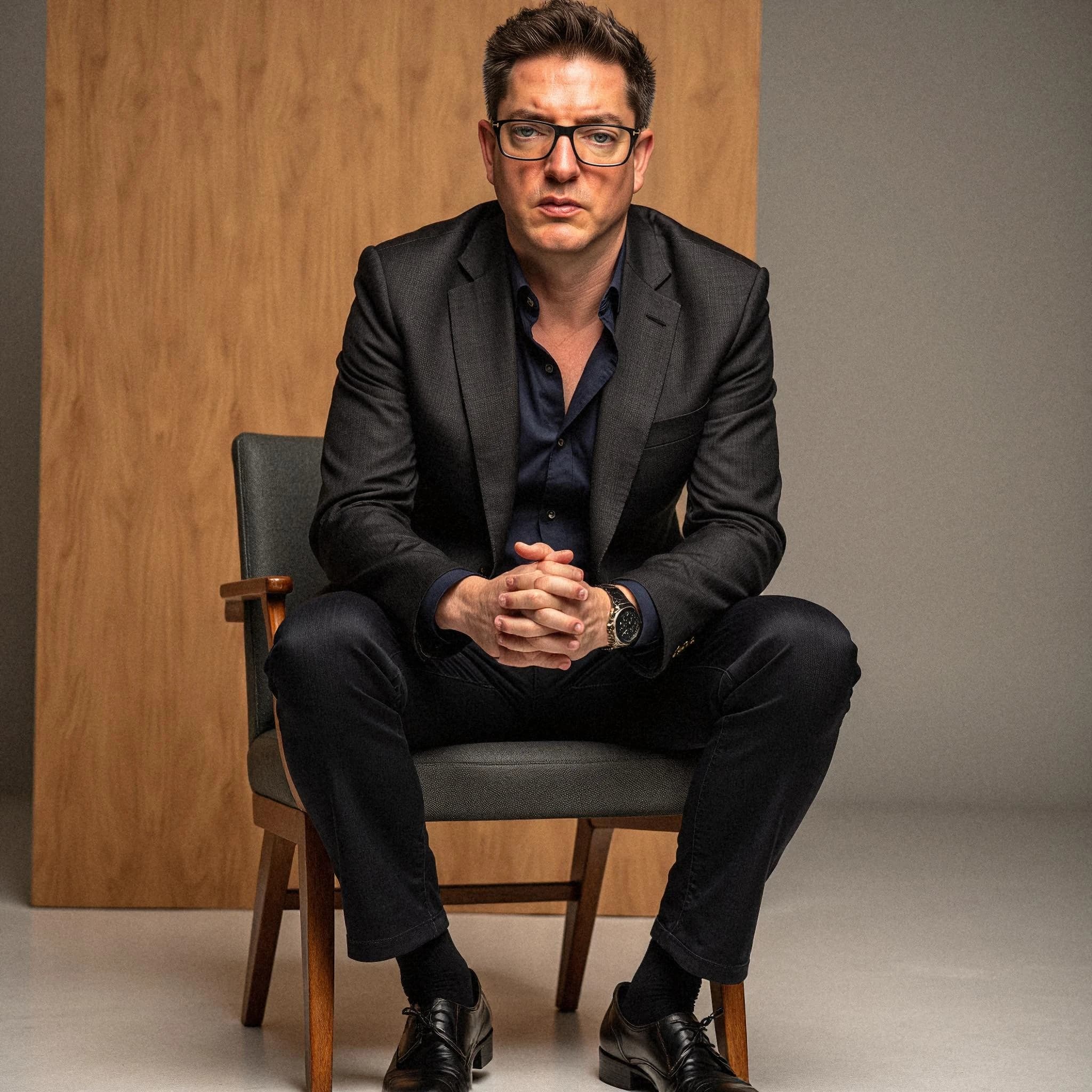 Professional headshot example: Man Studio Suit Sitting Chair — LinkedInHeadshots.ai