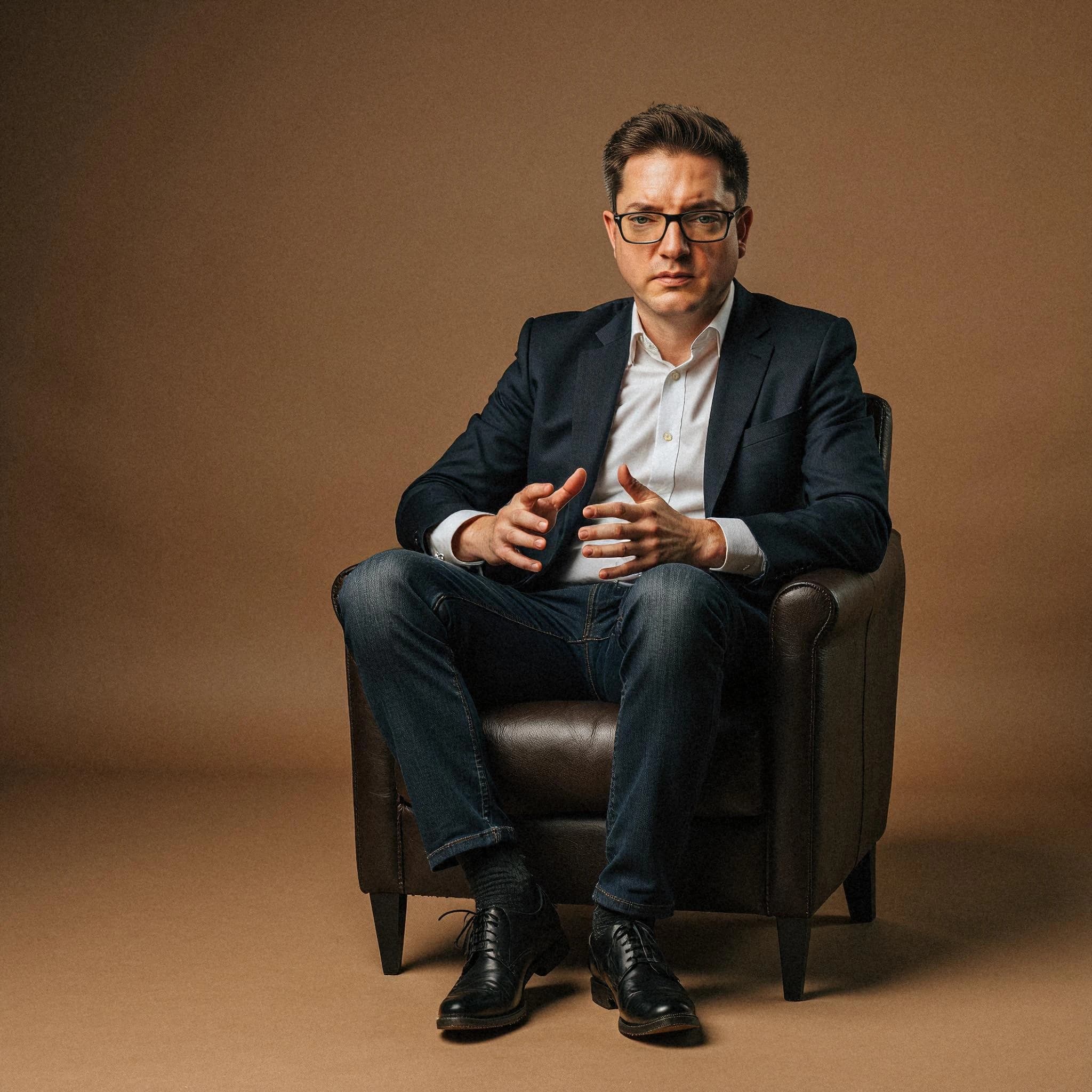 Professional headshot example: Man Studio Suit Sitting Chair 2 — LinkedInHeadshots.ai