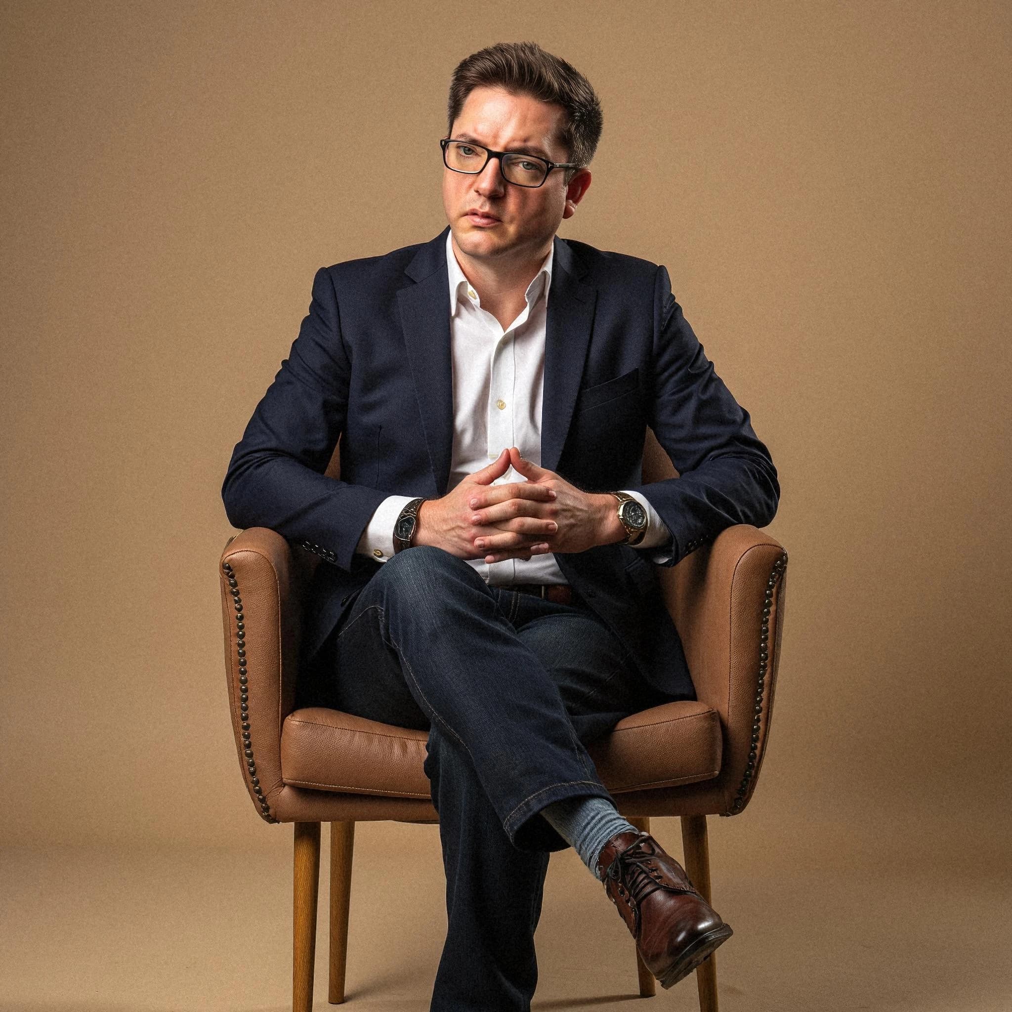 Professional headshot example: Man Studio Suit Sitting Chair 3 — LinkedInHeadshots.ai