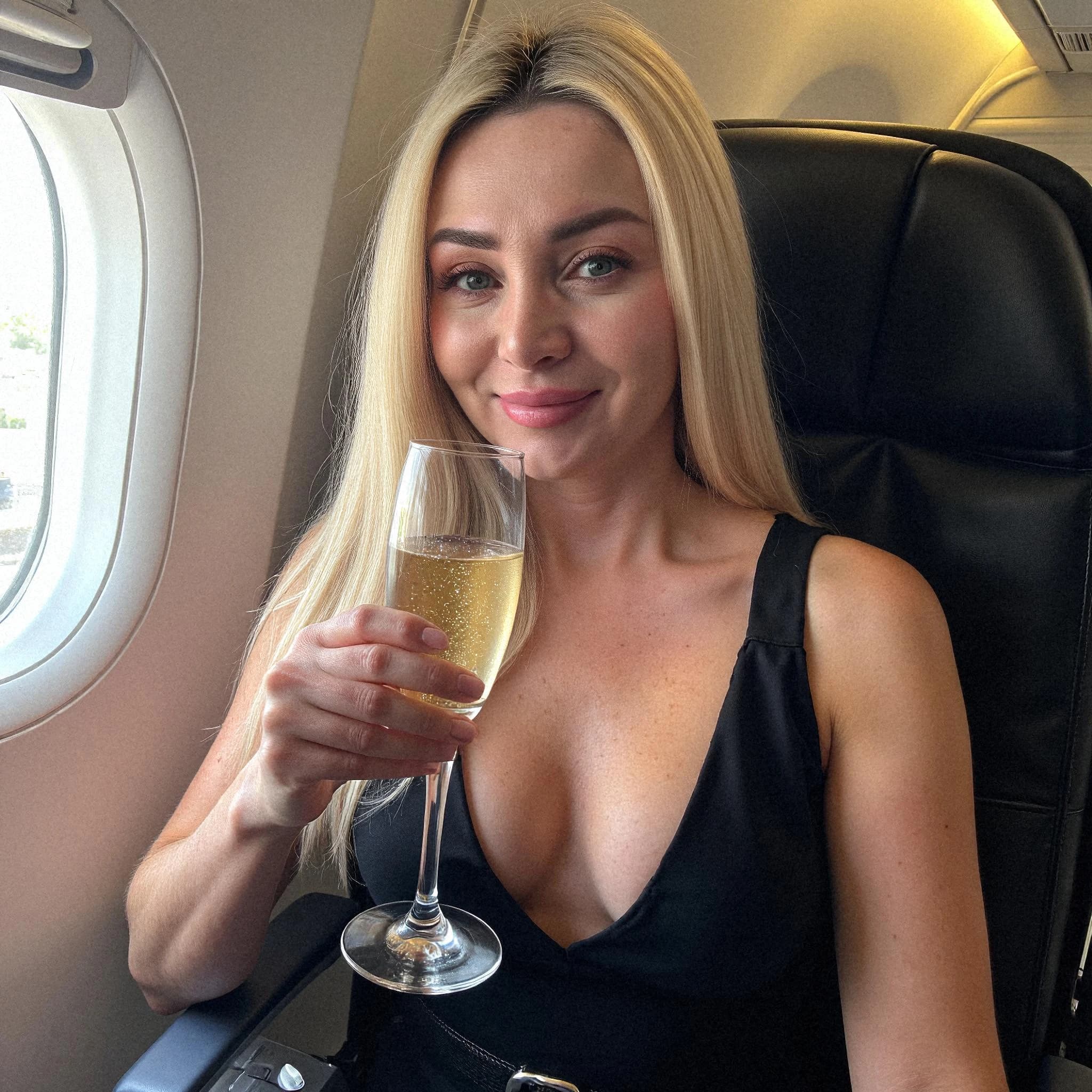 Professional headshot example: Woman Airplane Black Dress Holding Champagne — LinkedInHeadshots.ai