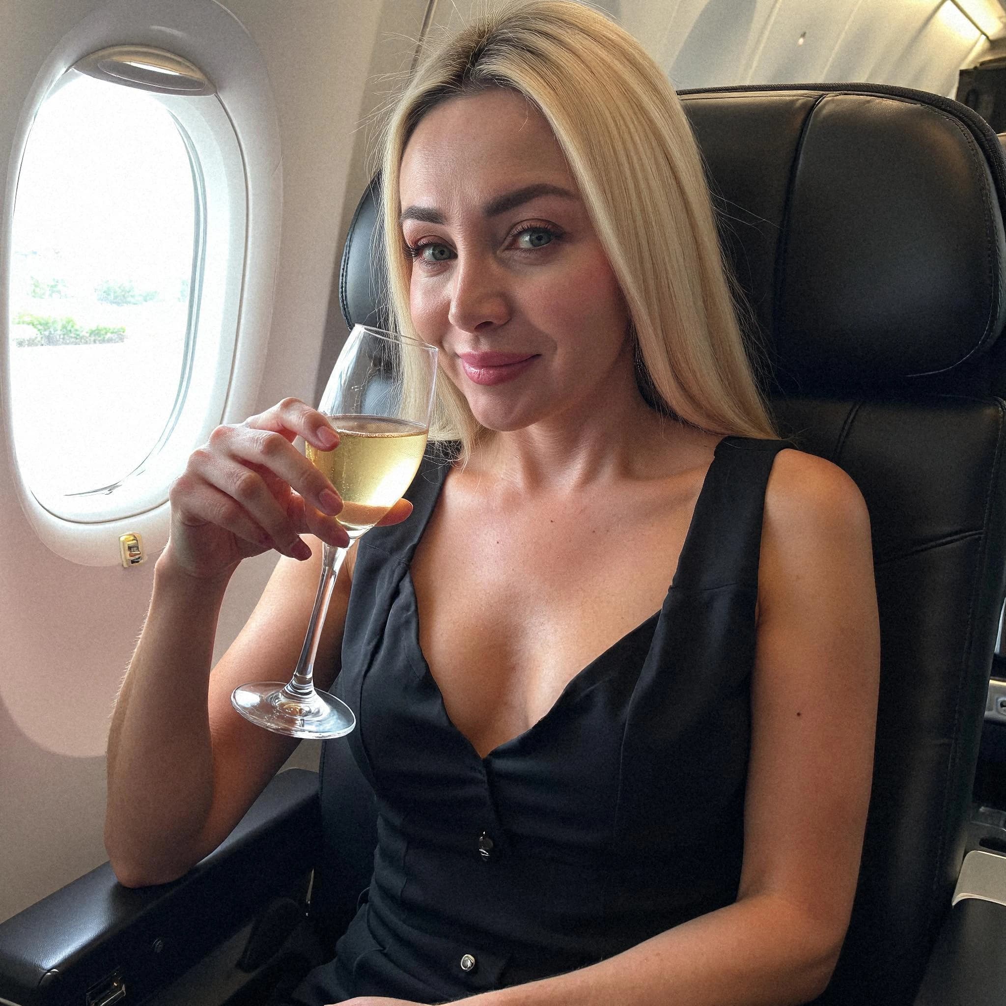 Professional headshot example: Woman Airplane Black Dress Holding Wine 2 — LinkedInHeadshots.ai