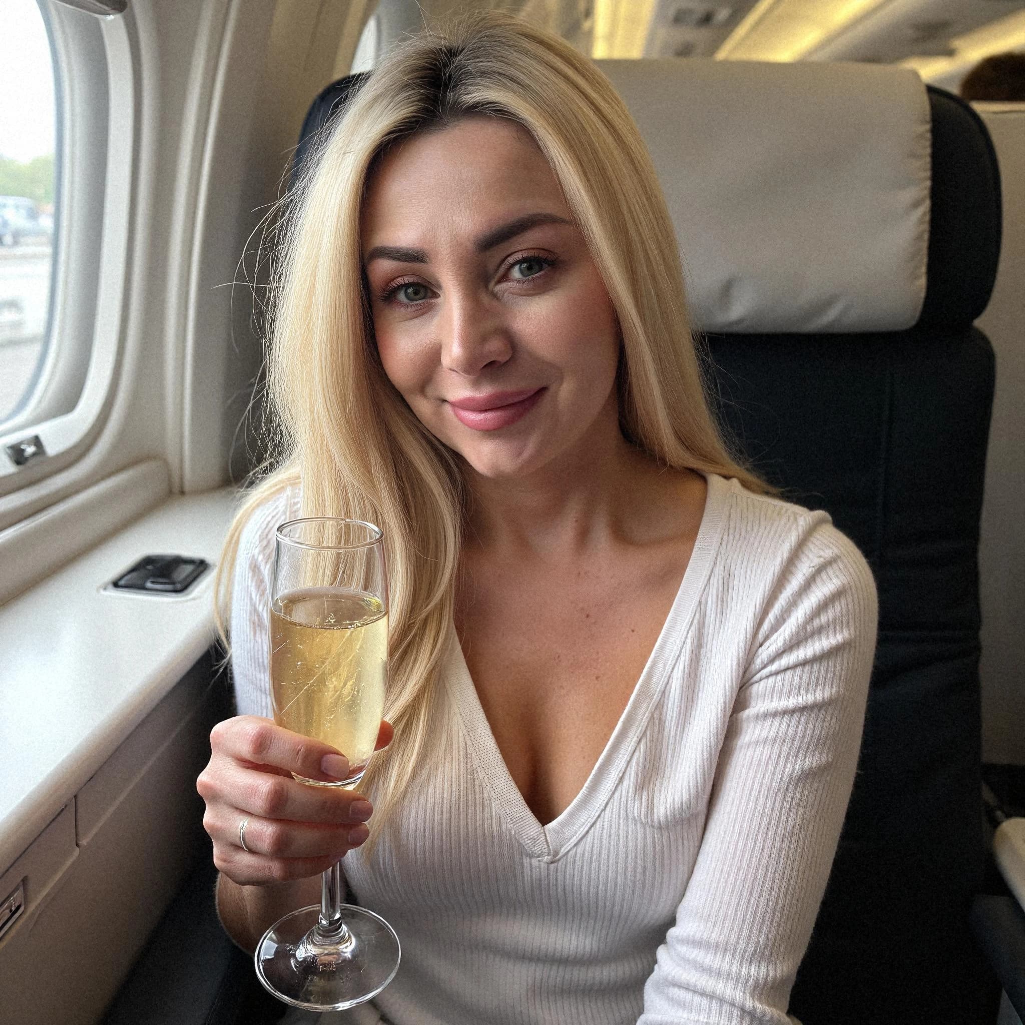 Professional headshot example: Woman Airplane White Top Holding Champagne 2 — LinkedInHeadshots.ai