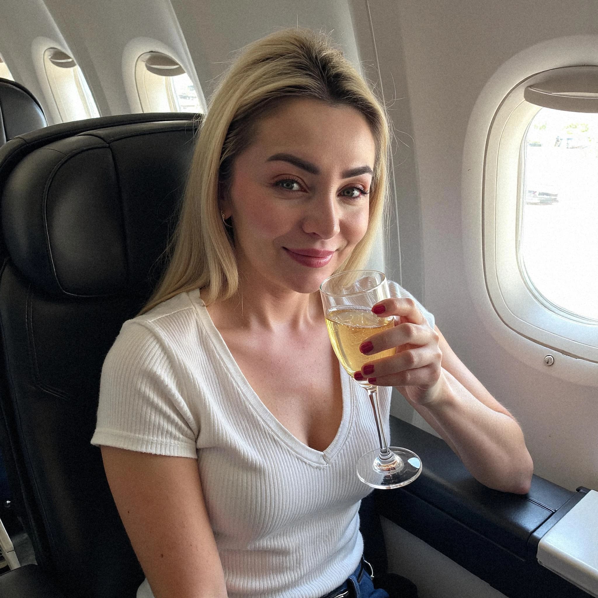 Professional headshot example: Woman Airplane White Top Holding Wine — LinkedInHeadshots.ai