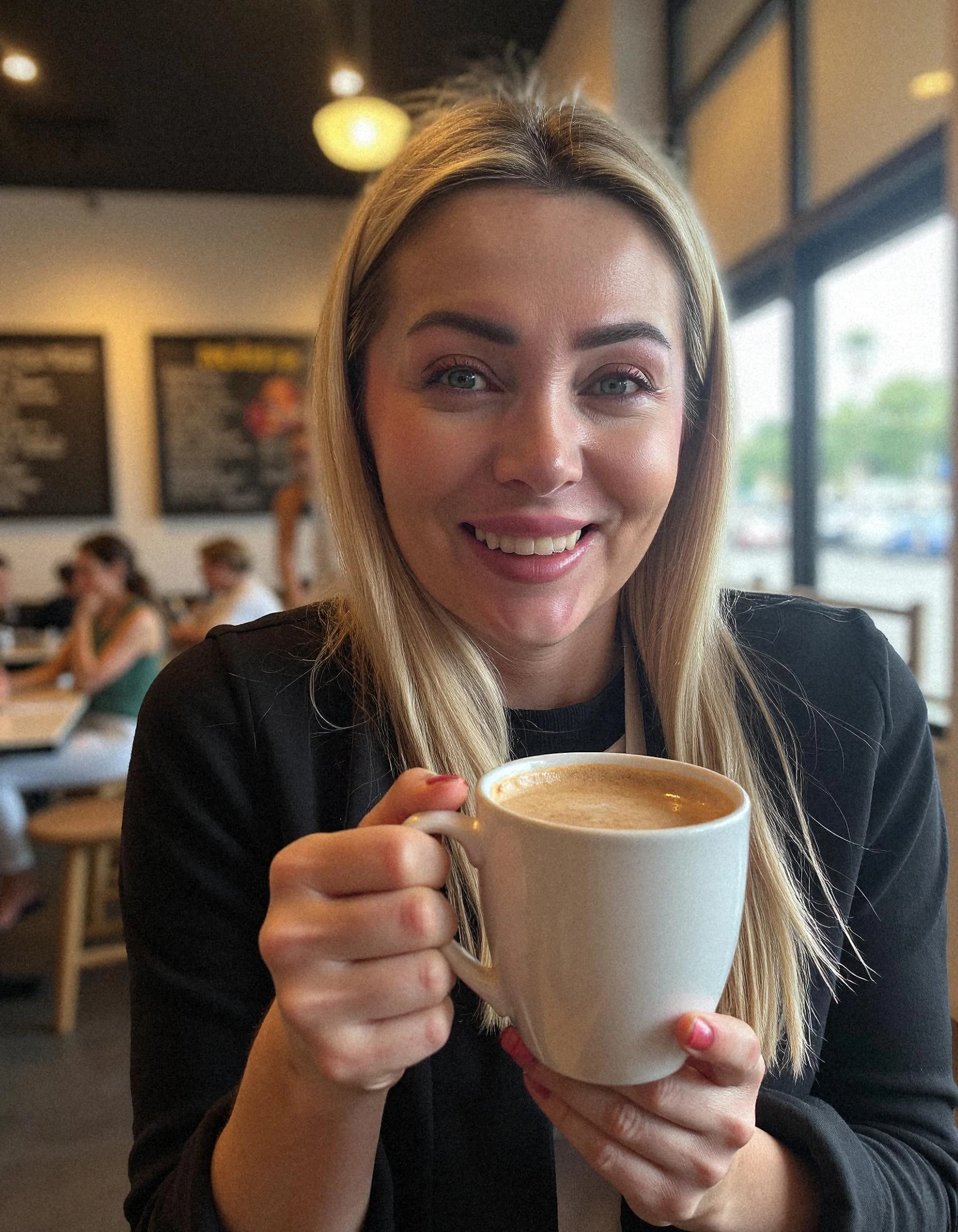 Professional headshot example: Woman Cafe Black Jacket Holding Coffee — LinkedInHeadshots.ai