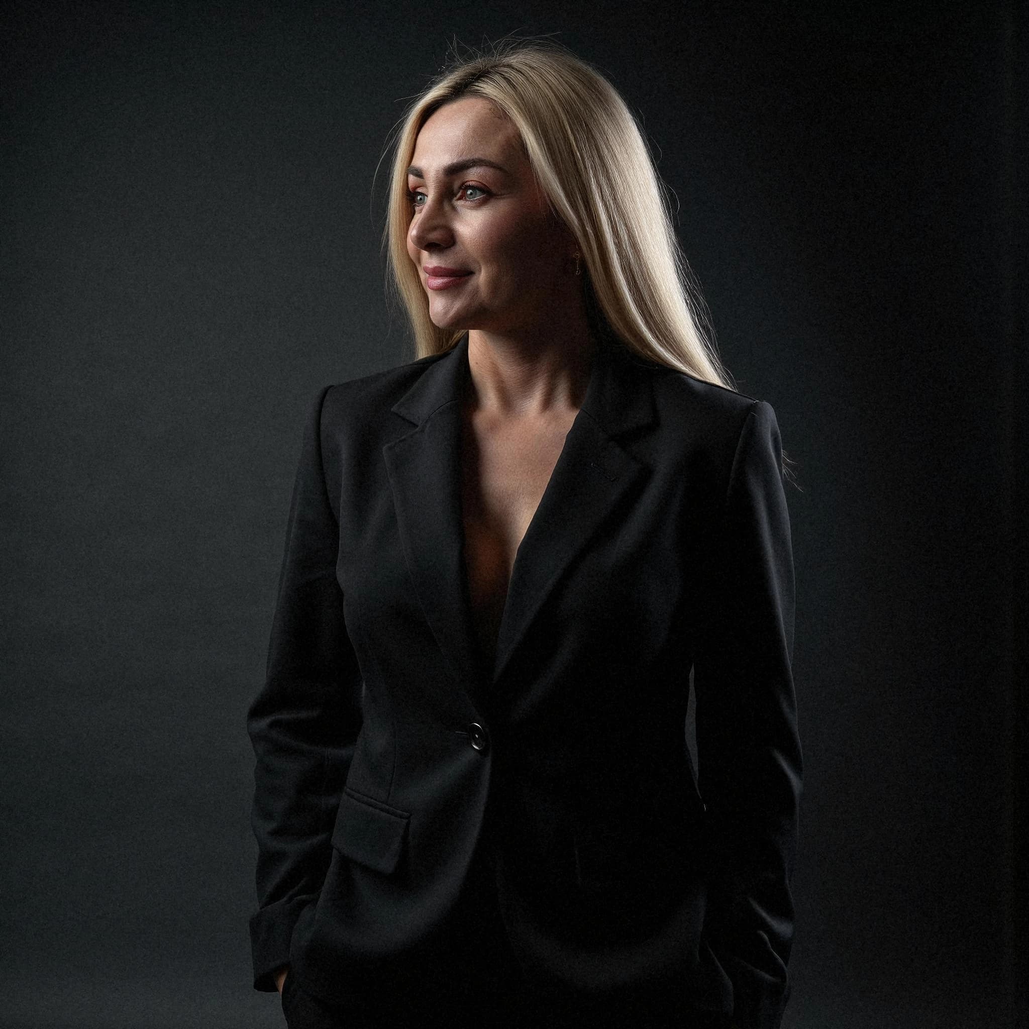 Professional headshot example: Woman Studio Black Suit Standing — LinkedInHeadshots.ai