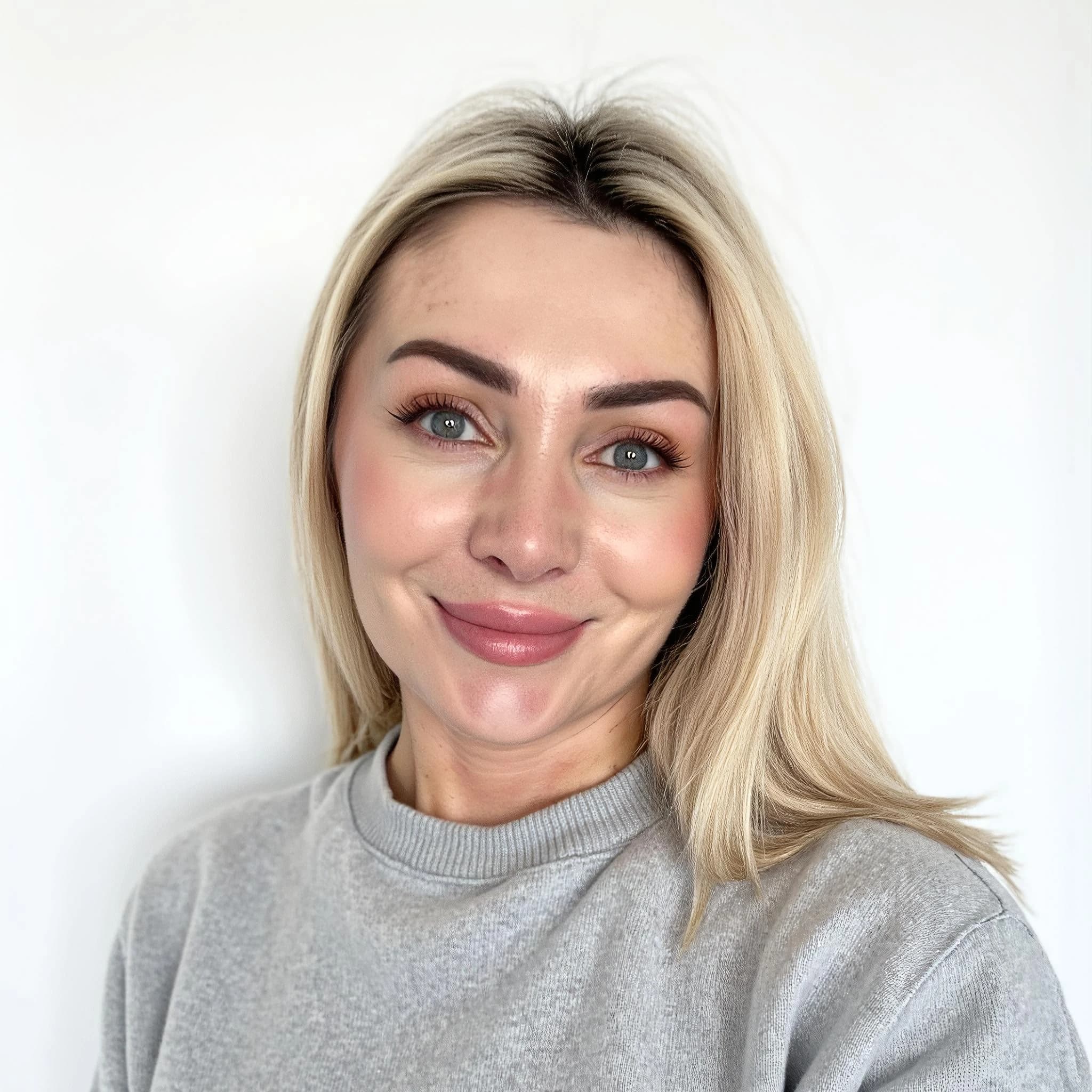 Professional headshot example: Woman White Background Grey Sweater Smiling — LinkedInHeadshots.ai